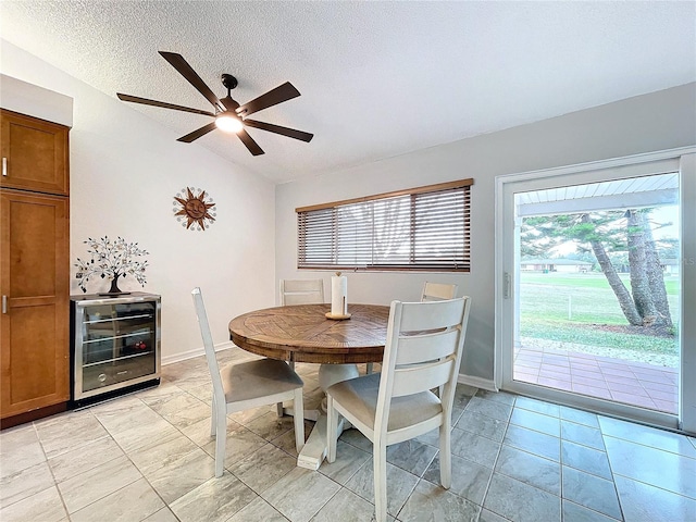 dining area with a textured ceiling, beverage cooler, ceiling fan, lofted ceiling, and light tile patterned flooring