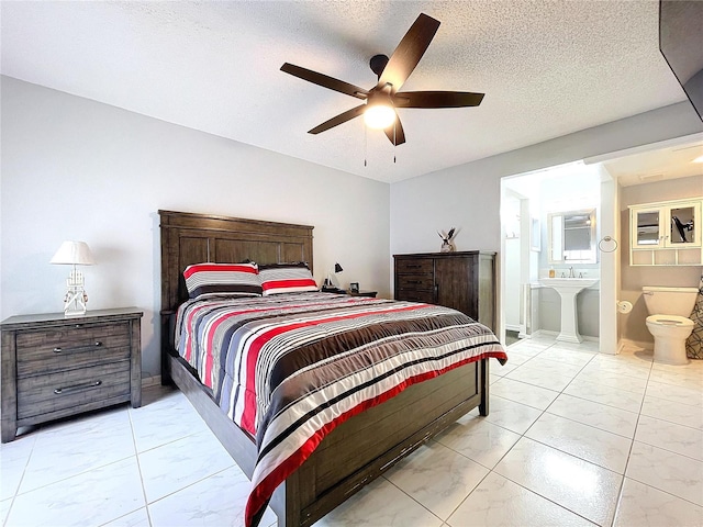 bedroom featuring ensuite bath, ceiling fan, and a textured ceiling