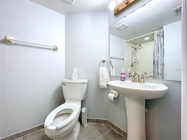 bathroom with tile patterned flooring, a textured ceiling, toilet, and a shower with shower curtain