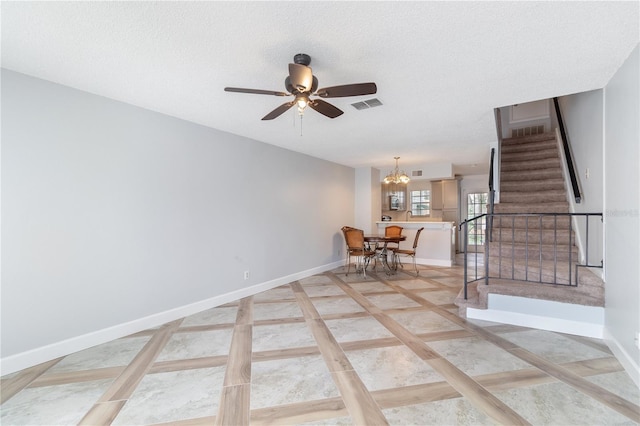 interior space featuring ceiling fan with notable chandelier and a textured ceiling