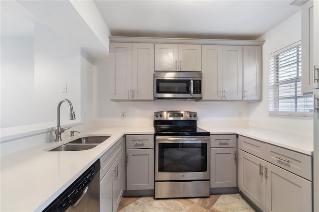 kitchen with gray cabinets, sink, and stainless steel appliances