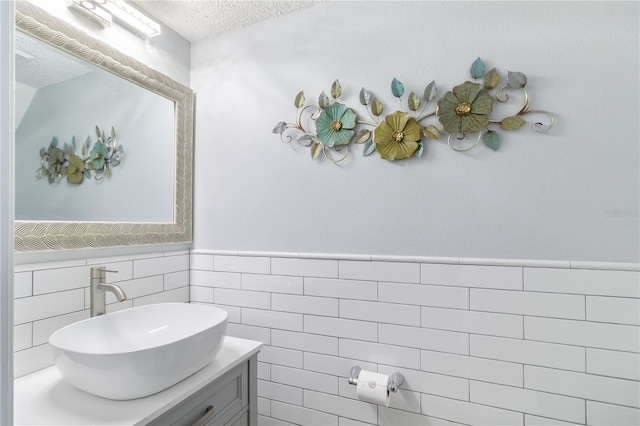 bathroom featuring vanity, a textured ceiling, and tile walls