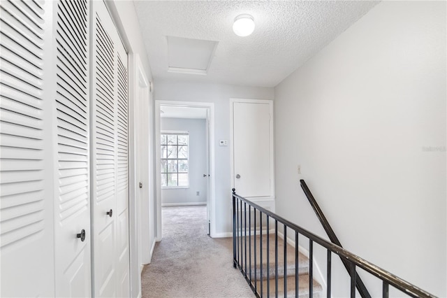 hallway featuring light carpet and a textured ceiling