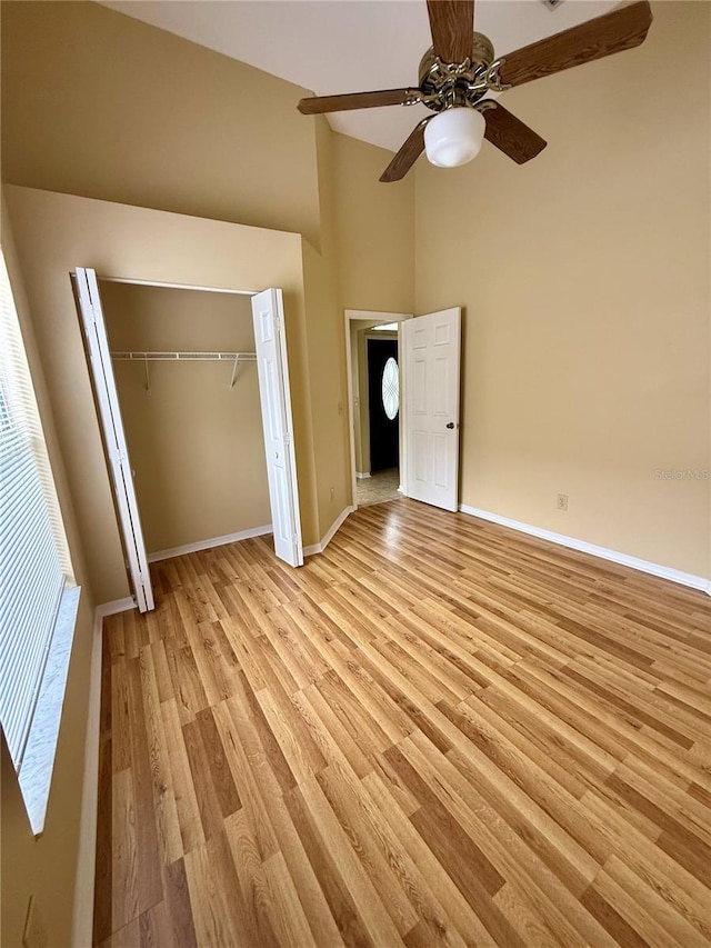 unfurnished bedroom with light wood-type flooring, a closet, high vaulted ceiling, and ceiling fan