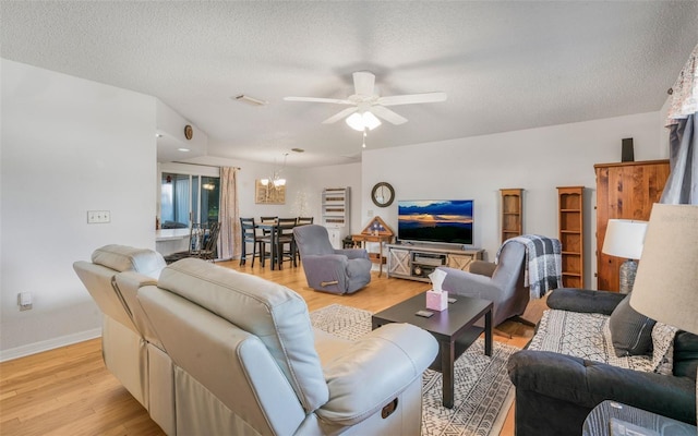 living room featuring a textured ceiling, light hardwood / wood-style flooring, and ceiling fan with notable chandelier