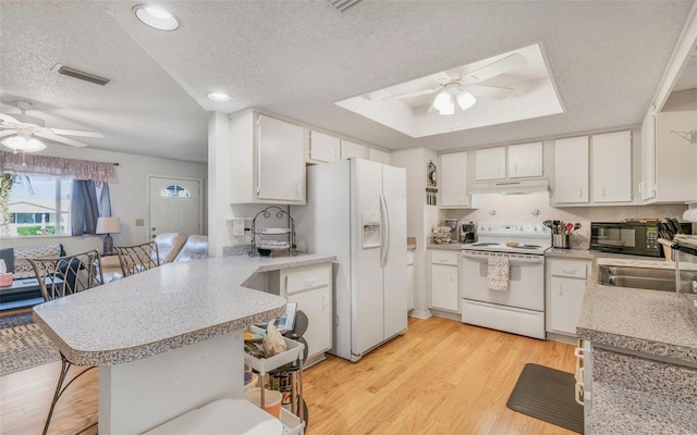 kitchen featuring kitchen peninsula, light wood-type flooring, a textured ceiling, white appliances, and white cabinets