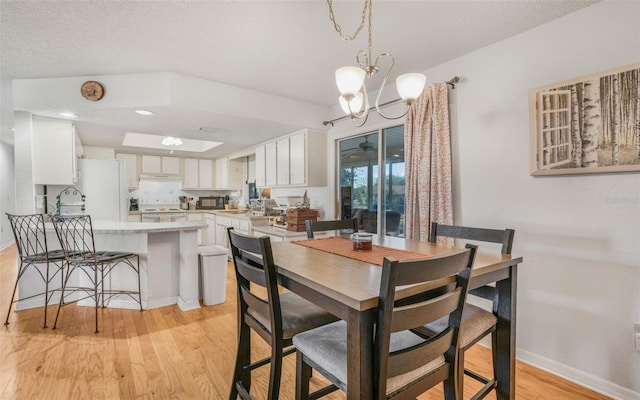 dining room with a textured ceiling, light hardwood / wood-style floors, sink, and an inviting chandelier