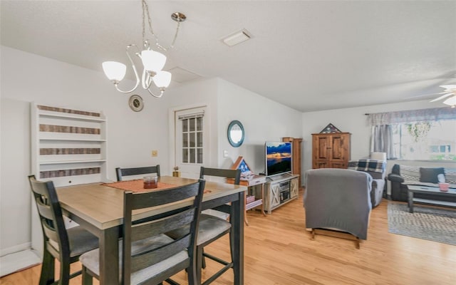 dining space featuring a textured ceiling, light hardwood / wood-style flooring, and ceiling fan with notable chandelier