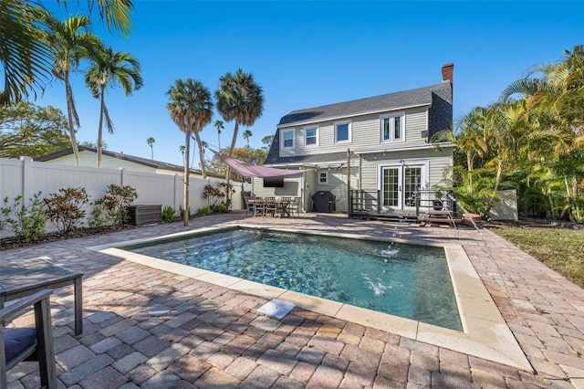 rear view of property with a fenced in pool, a patio area, and pool water feature