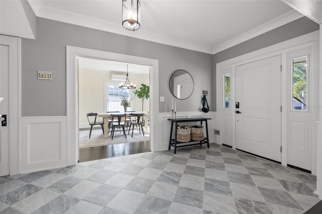 entrance foyer featuring plenty of natural light, an inviting chandelier, and ornamental molding