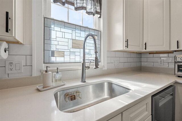 kitchen with white cabinets, dishwashing machine, backsplash, and sink