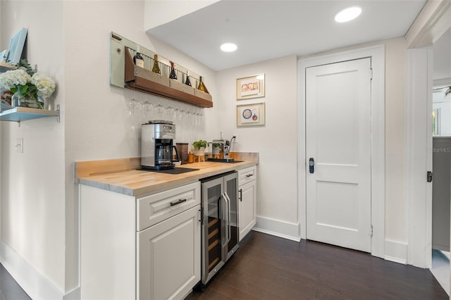 bar with dark wood-type flooring, white cabinetry, wine cooler, and butcher block counters