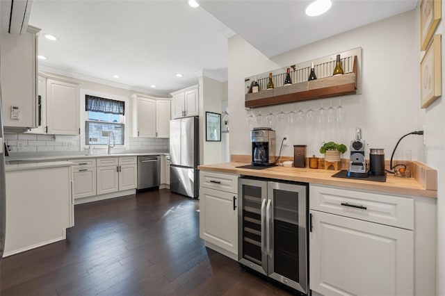 bar with white cabinetry, sink, beverage cooler, wooden counters, and appliances with stainless steel finishes