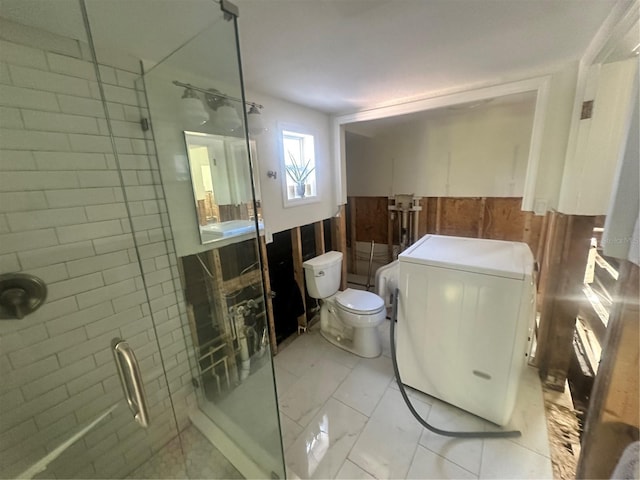 bathroom with washer / clothes dryer, a shower with door, and toilet