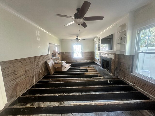 stairs featuring a wealth of natural light, built in features, ceiling fan, and ornamental molding