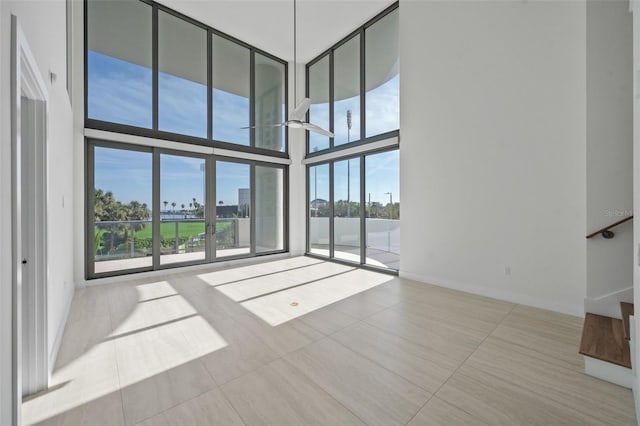 empty room featuring a towering ceiling and floor to ceiling windows