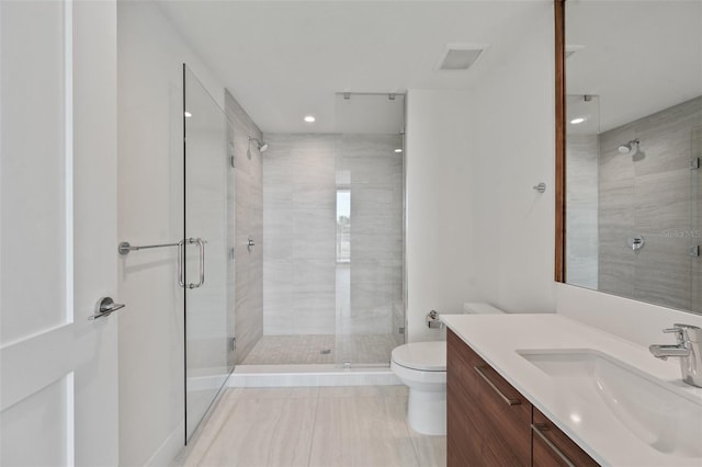 bathroom featuring tile patterned flooring, vanity, toilet, and a shower with door