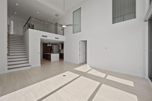 unfurnished living room with sink, light tile patterned floors, and a high ceiling