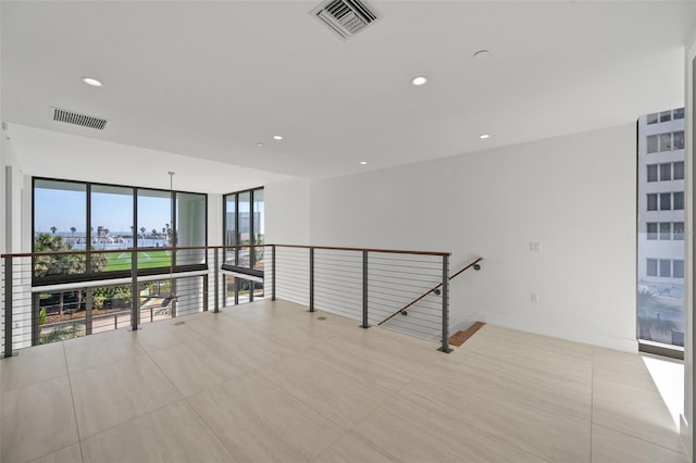 empty room featuring expansive windows and light tile patterned flooring