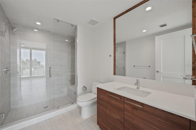 bathroom featuring tile patterned floors, vanity, toilet, and a shower with door