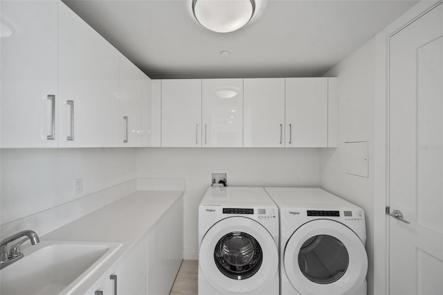 washroom with washer and clothes dryer, sink, cabinets, and light hardwood / wood-style floors