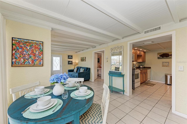 tiled dining area featuring plenty of natural light and beam ceiling