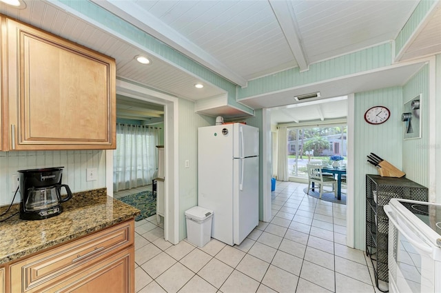 kitchen featuring beamed ceiling, light tile patterned floors, white appliances, and dark stone countertops