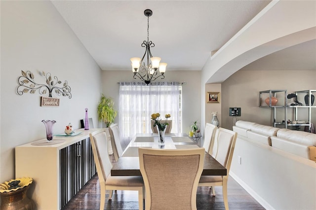 dining space featuring dark wood-type flooring and an inviting chandelier