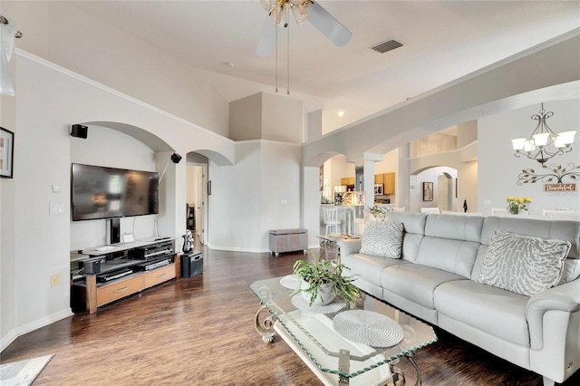 living room with ceiling fan with notable chandelier, dark wood-type flooring, and a high ceiling