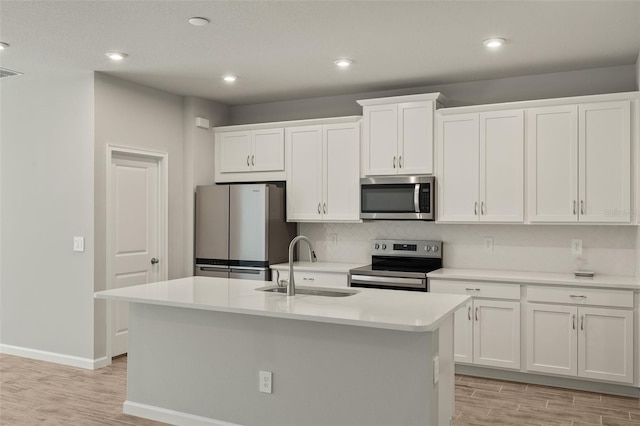 kitchen featuring appliances with stainless steel finishes, a kitchen island with sink, sink, and white cabinets