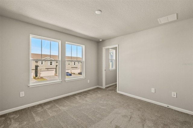 carpeted spare room featuring a textured ceiling