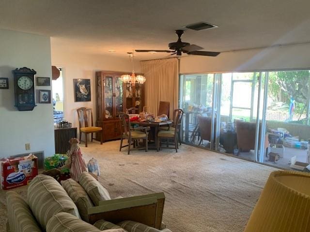 living room featuring carpet flooring and ceiling fan with notable chandelier