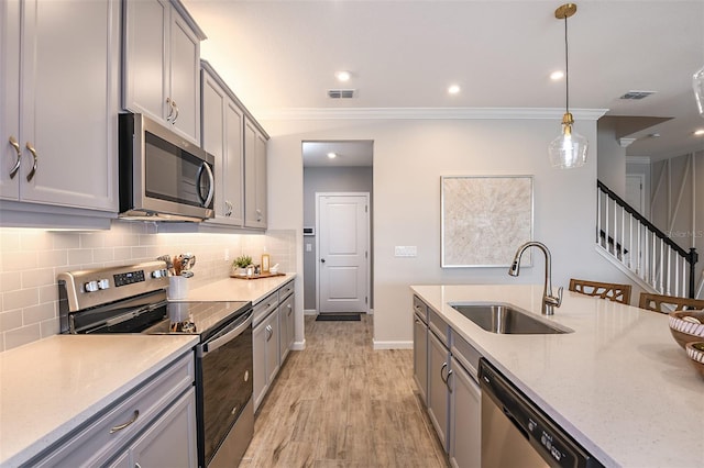 kitchen with gray cabinetry, sink, stainless steel appliances, light hardwood / wood-style flooring, and decorative light fixtures