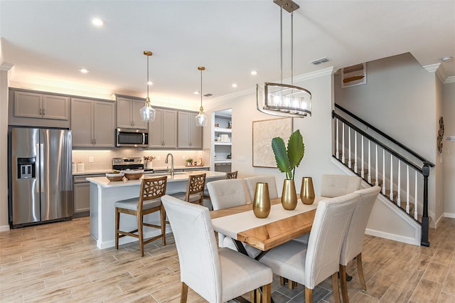 dining room with light hardwood / wood-style floors, ornamental molding, and sink