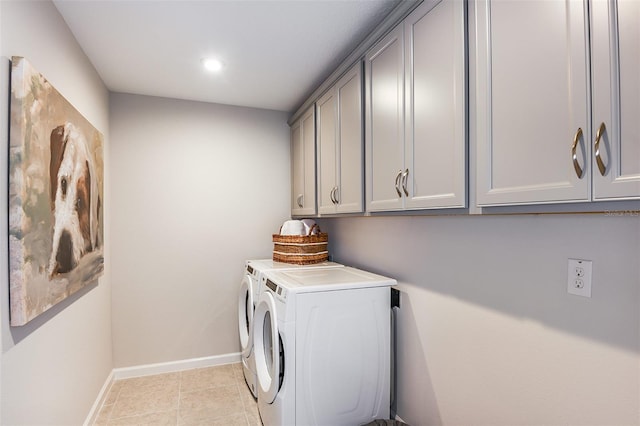 laundry area with washing machine and clothes dryer, light tile patterned floors, and cabinets