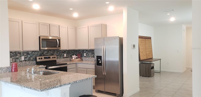 kitchen featuring backsplash, light tile patterned floors, light stone counters, kitchen peninsula, and stainless steel appliances