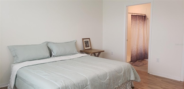 bedroom featuring connected bathroom and light hardwood / wood-style floors