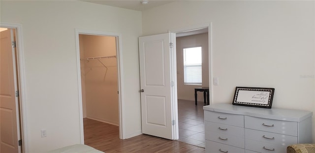 unfurnished bedroom with light hardwood / wood-style floors, a walk in closet, and a closet