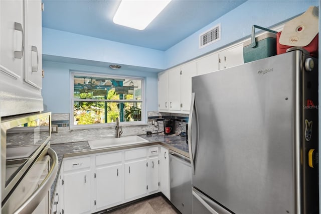 kitchen featuring appliances with stainless steel finishes, sink, white cabinets, and backsplash