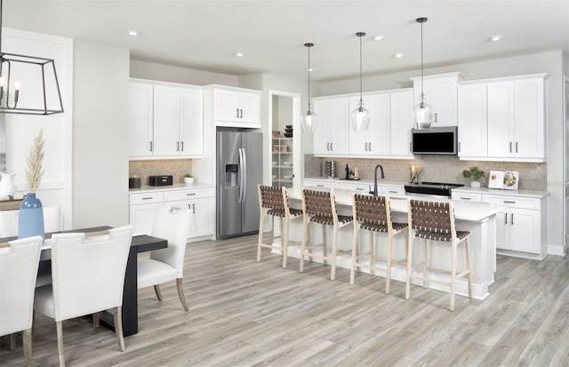 12458 49th St E, Parrish, FL 34219 - kitchen with stainless steel refrigerator with ice dispenser, light countertops, backsplash, light wood-style floors, and recessed lighting