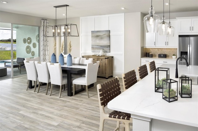 dining room with sink, light hardwood / wood-style floors, and a notable chandelier