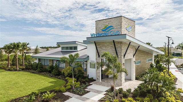 12458 49th St E, Parrish, FL 34219 - view of front of home with a standing seam roof, a front yard, a chimney, a metal roof, and stone siding