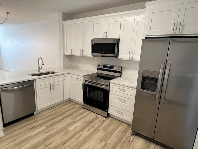 kitchen featuring a textured ceiling, white cabinetry, sink, and appliances with stainless steel finishes