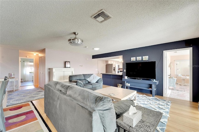 living room with a textured ceiling and light wood-type flooring