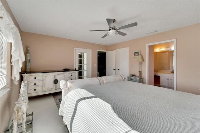 bedroom with ceiling fan, a wall mounted AC, connected bathroom, built in desk, and a textured ceiling