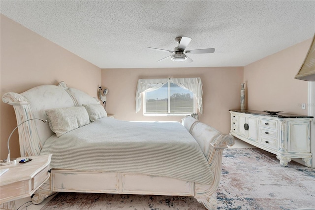 bedroom with ceiling fan and a textured ceiling