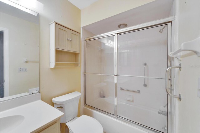 full bathroom featuring vanity, bath / shower combo with glass door, and toilet