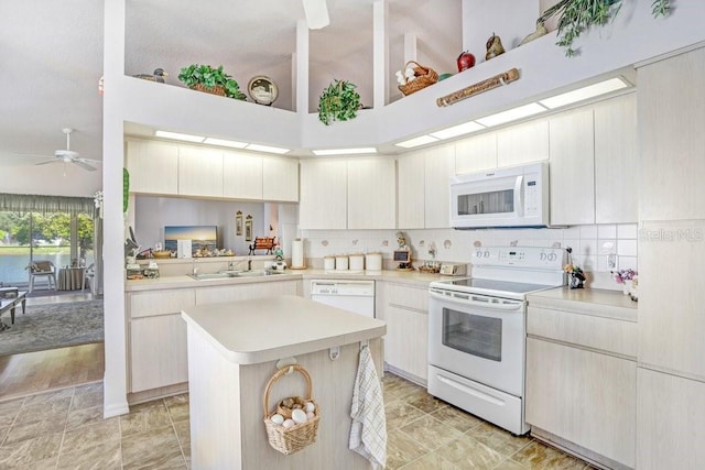 kitchen with kitchen peninsula, white appliances, ceiling fan, sink, and a center island