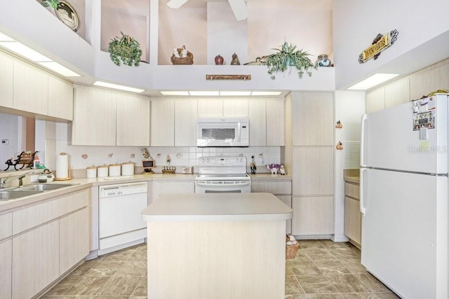 kitchen featuring decorative backsplash, white appliances, sink, a high ceiling, and a center island