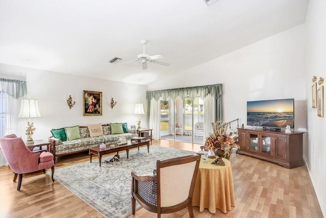 living room with ceiling fan, vaulted ceiling, and light wood-type flooring